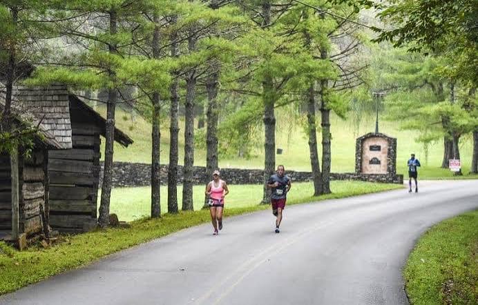 Runners passing a log cabin on the Great Smoky Mountains Half Marathon course