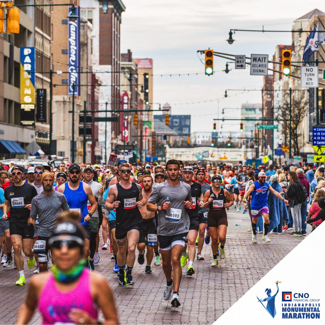 A big pack of runners on a brick street in downtown Indianapolis during the Monumental Marathon