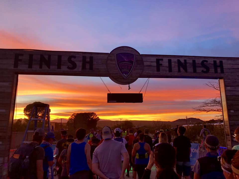 Runners at the Joshua Tree Half Marathon finish arch at sunset