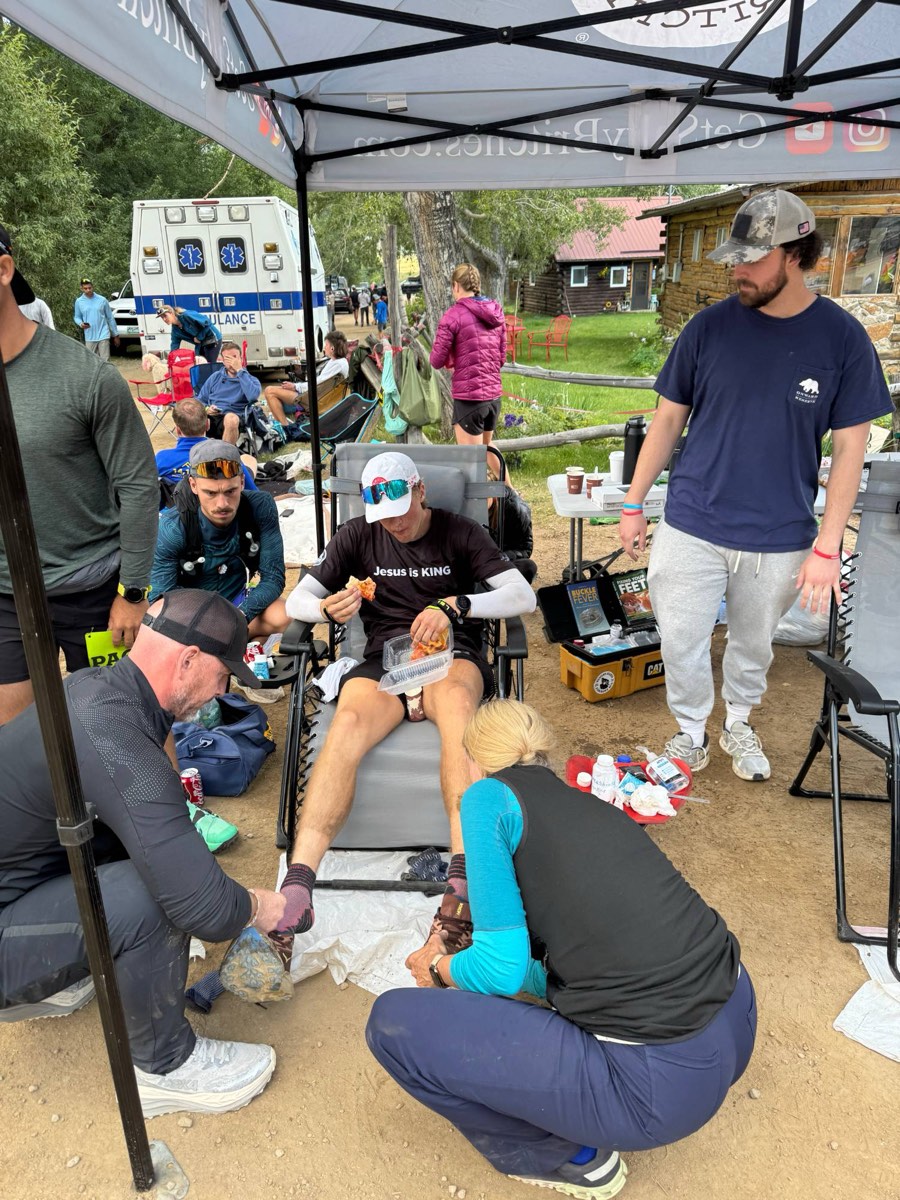 Pierce Showe in a chair at a Leadville aid station while his crew cares for his feet