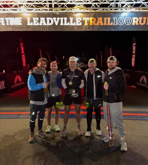 Runner and pacers at the Leadville Trail 100 finish line with a finisher buckle