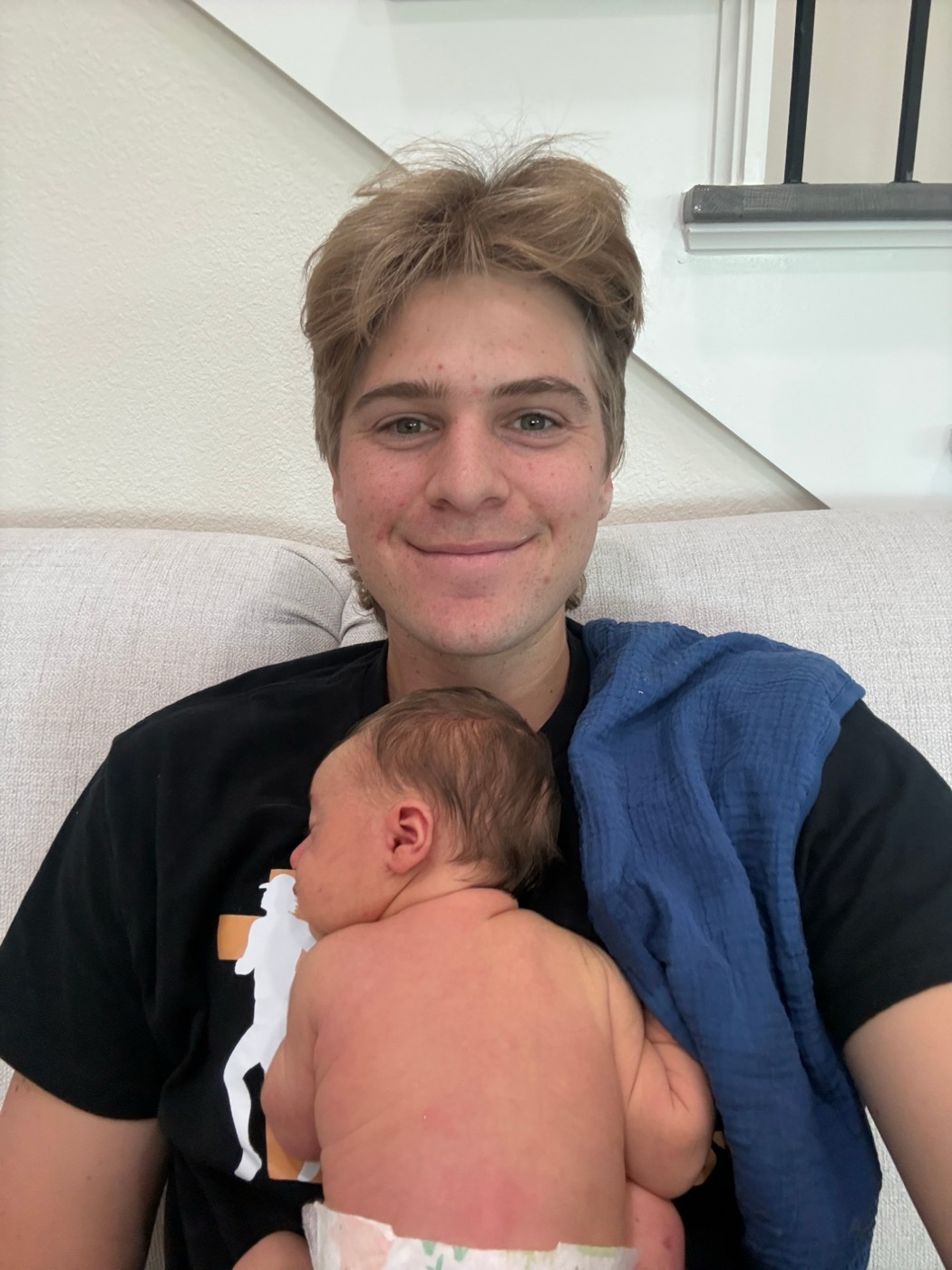 Pierce Showe on the couch with his newborn son John asleep on his chest