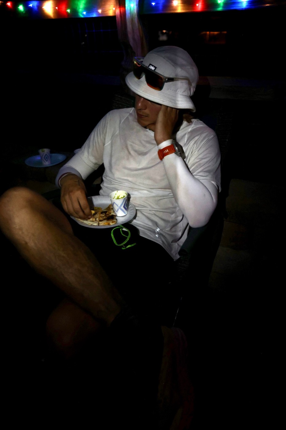 Pierce Showe sitting in a chair at night eating a quesadilla during the Tahoe 200