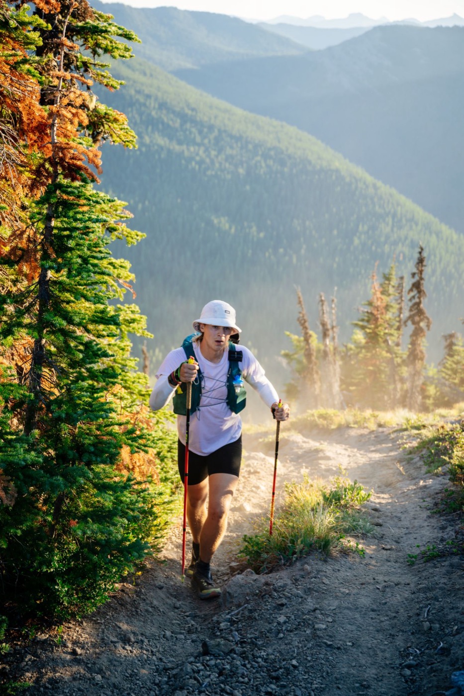 Pierce Showe climbing a mountain trail with trekking poles during a 200-mile race