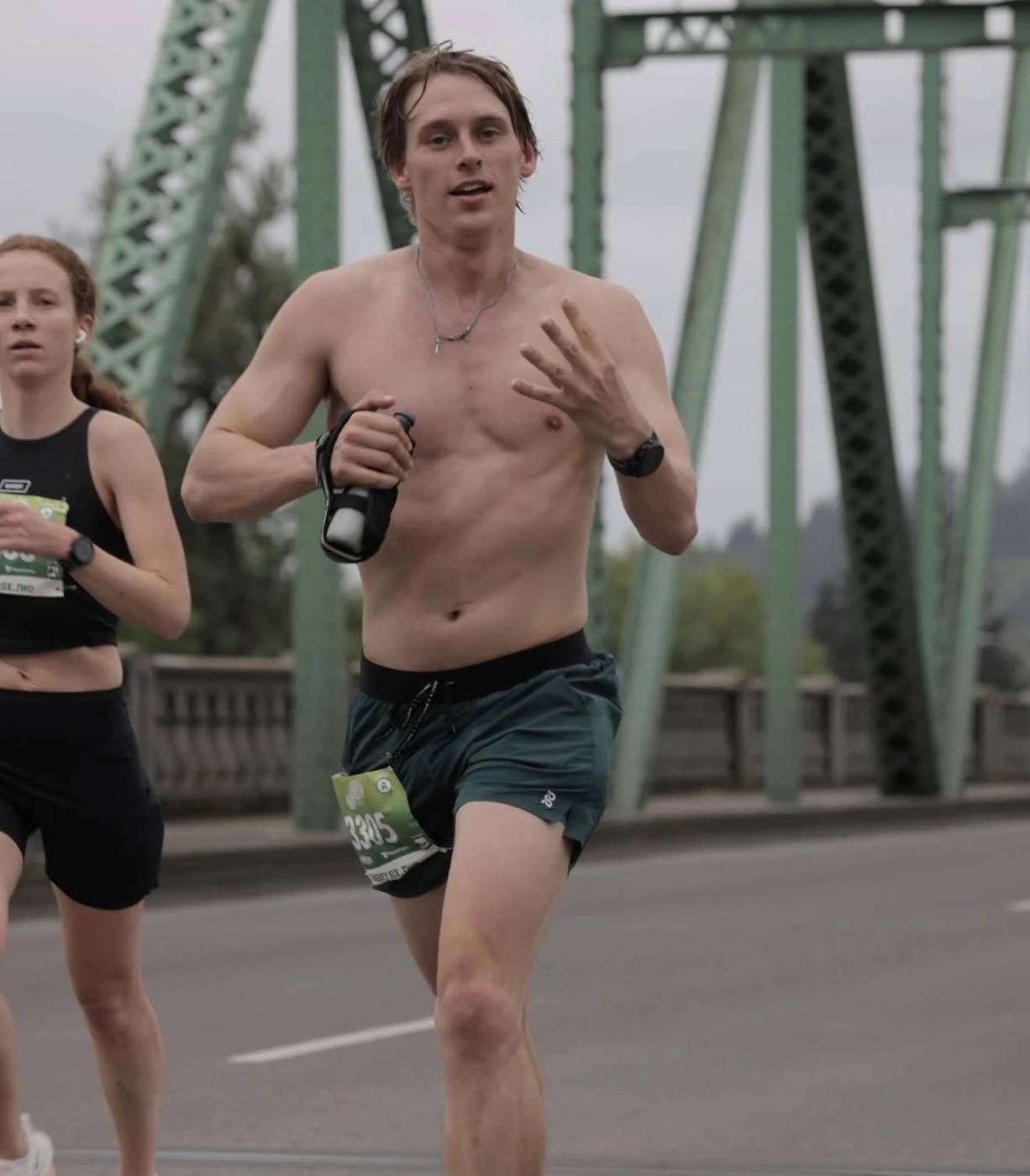 Robert Ross running across a green steel bridge during the Eugene Marathon