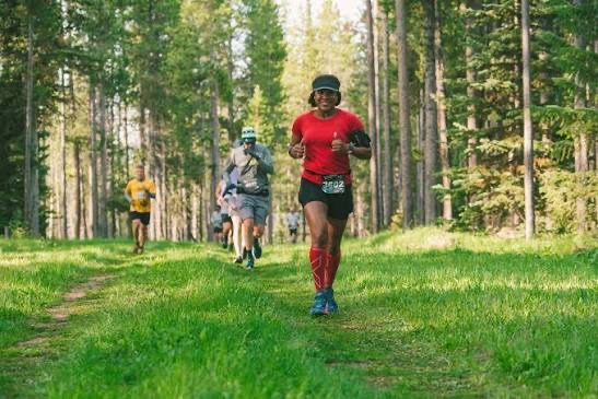 Runners on a grassy forest trail during the Yellowstone Half Marathon